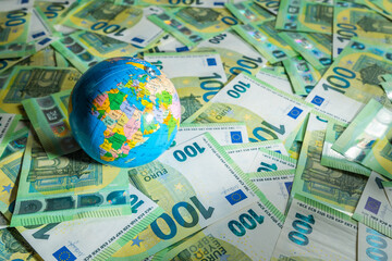 Globe map over many money bills with background of 100 euros - obrazy, fototapety, plakaty