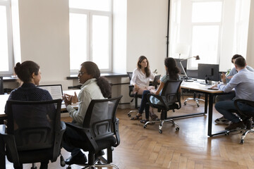 Pairs of diverse business colleagues working in modern office space, sitting at workplace desks,...
