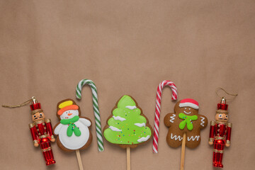 Christmas background for congratulations and cards. Gingerbread, candy cane and Nutcracker soldier lie on a brown craft paper background. There is space for text