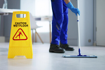 Male Janitor Cleaning Floor With Caution Wet Floor Sign - obrazy, fototapety, plakaty