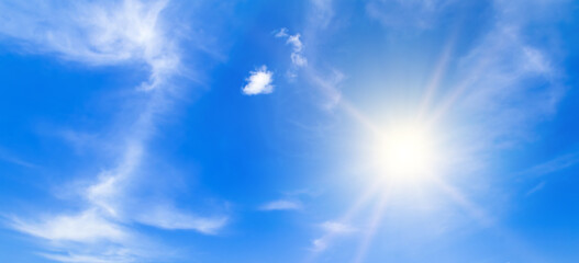 Naklejka na ściany i meble Light clouds and bright sun on a blue sky. Wide photo.