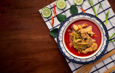Top view of red curry with pork belly and water spinach in bowl on wooden table background. ( GANG TAY PO ) Thai Food