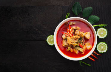 Top view of red curry with pork belly and water spinach in bowl on wooden table background. ( GANG TAY PO ) Thai Food