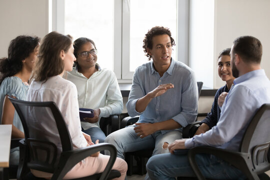 Motivated inspired business team employee man talking to colleague, convincing, gesturing, sharing ideas to project staff. Group of addicts meeting for therapy, social support, discussing problems