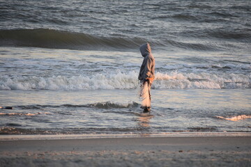 Man standing in water on the beach with crab net