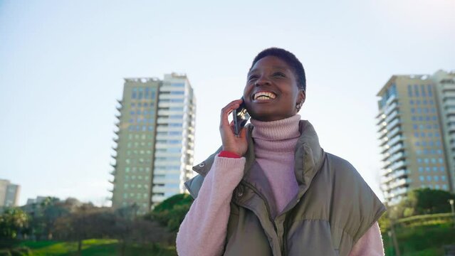 Young black woman having a call by smart phone outdoors. Communication concept. High quality 4k footage