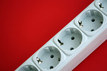 White electrical multi plug extender with european socket on bright red background close up