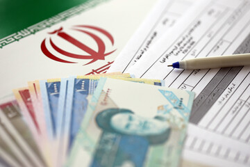 Iranian annual income tax return form F20-25-006 ready to fill on table with pen and iranian money...