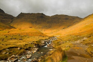 Beautiful shot of a rocky stream through orange brown mountains in the Lake District