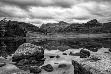 Grayscale shot of a pond near mountains in Blea Tarn, Lake District, UK