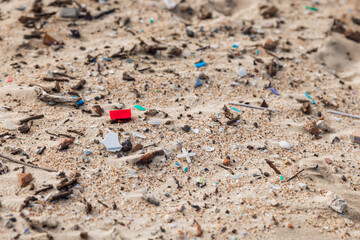 Fototapeta na wymiar Plastic trash in sand on beach. Pollution by microplastic rubbish on coastline