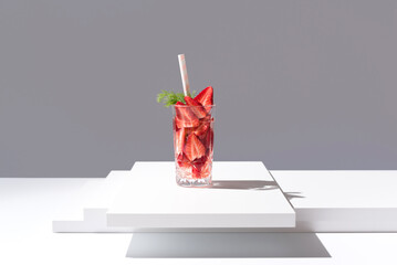 C&oacute;ctel de fresas en un vaso con paja sobre fondo gris	