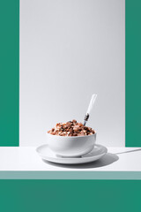 Cereal de granola muesli en un tazón blanco con cuchara sobre fondo verde