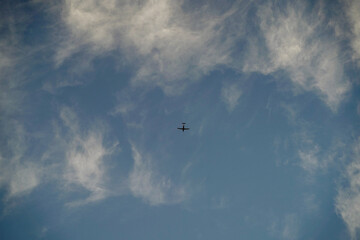 small airplane flying on the blue cloudy sky