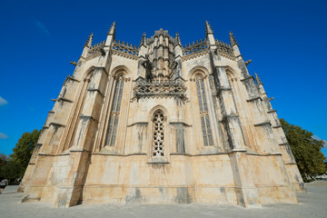 Klasztor Batalha, Portugalia. Monumentalne, sakralne dzieło architektoniczne. Perspektywa, linie zbieżne, jaste, piaskowe, strzeliste wieżyczki. na tle granatowego nieba - obrazy, fototapety, plakaty
