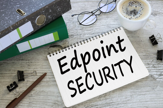 Endpoint Security a cup of coffee. glasses. two office folder gray notepad. text on the page