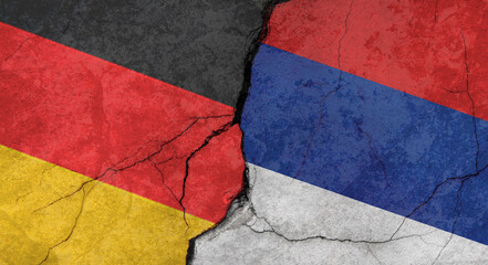 Germany and Serbia flags, concrete wall texture with cracks, orange background, military conflict concept