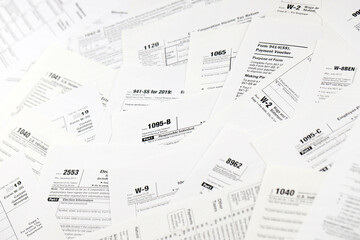 Many tax form blanks lies on table close up. Tax payers paperwork routine and bureaucracy concept....