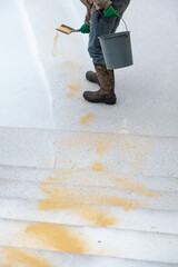 Worker sprinkles dry sand on slippery path in yard