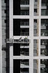 Construction workers on a lift platform work