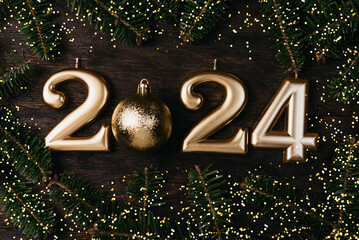 Holiday background Happy New Year 2024. Numbers of year 2024 made by gold candles wooden rustic background with fir tree. celebrating New Year holiday, close-up. Space for text