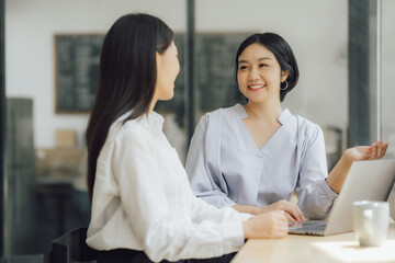 Beautiful young smiling Asian businesswoman working on laptop and drinking coffee, Asia businesswoman working document finance and calculator in her office.
