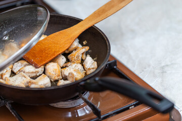 chicken breasts meat only on frying pan and wooden spatula, domestic healthy cuisine in real life situation.