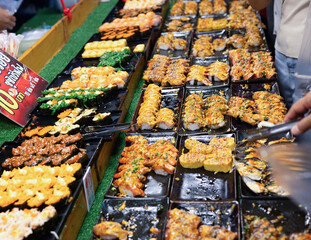 Customer picks up sushi on a box in the street food market.