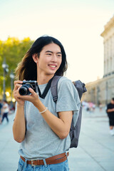 Asian male tourist smiling with his camera while sightseeing in Madrid, Spain.