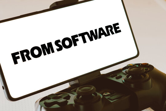 November 11, 2023, Brazil. In this photo illustration, the FromSoftware logo is displayed on a smartphone screen, next to a gamepad.