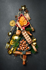 Christmas baking background with fir tree made from kitchen utensils, cookies, spices, cinnamon sticks, anise stars on rustic baking tray, top view - obrazy, fototapety, plakaty