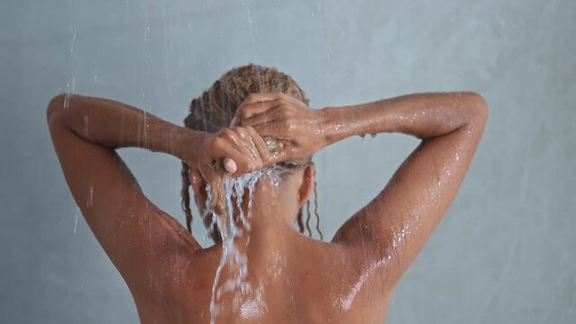 rear view woman washing blond curly hair slow motion morning routine