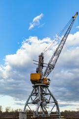 Crane with the bright cloudy sky in the background - an industrial concept