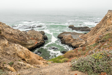 Rugged Pacific coast o Oregon with fog rolling in from the ocean and crashing waves.