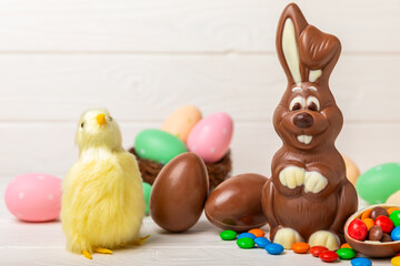 Easter chocolate bunny on a light texture table. Chocolate eggs and other sweets. Easter celebration concept. Easter sweets on the table. Place for text. copy space.