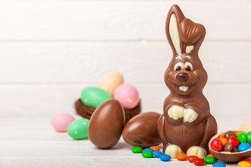 Easter chocolate bunny on a light texture table. Chocolate eggs and other sweets. Easter celebration concept. Easter sweets on the table. Place for text. copy space.