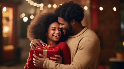 Couple in cozy sweaters, sharing a moment of joy and affection as they exchange a Christmas gift, with a festively decorated tree and warm lights in the background.