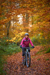 Fototapeta premium nice senior woman riding her electric mountainbike on the autumnal forest trails near Stuttgart,Baden-Wuerttemberg, Germany
