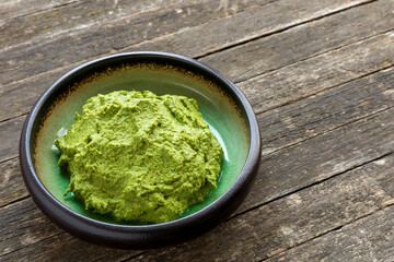 Green herbs chutney in a bowl on rustic table.