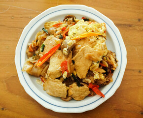 Pad See Ew-stir-fried noodles with black soy sauce and chicken on a wooden background, Top down view of Thai food