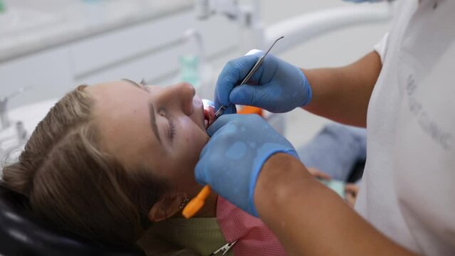 Male dentist treating teeth to young woman patient in clinic. Dental check up.