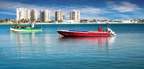 Red and green, pleasure motor boats, against the backdrop of a sea city