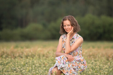 Portrait of a young beautiful girl in a light dress on a summer field.