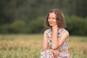 Fototapeta na wymiar Portrait of a young beautiful girl in a light dress on a summer field.