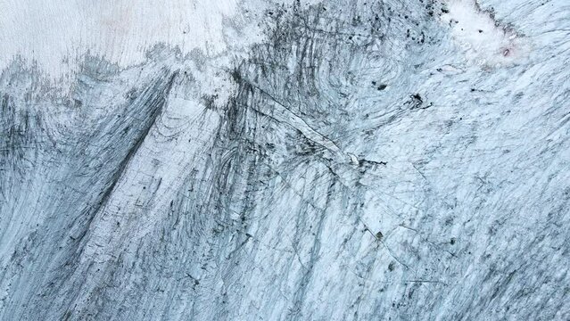 Aerial top view of blue alpine glacier texture and crevasses