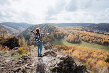 Girl standing on the edge of the mountain and enjoying the sun, relaxing in the mountains, hiking...