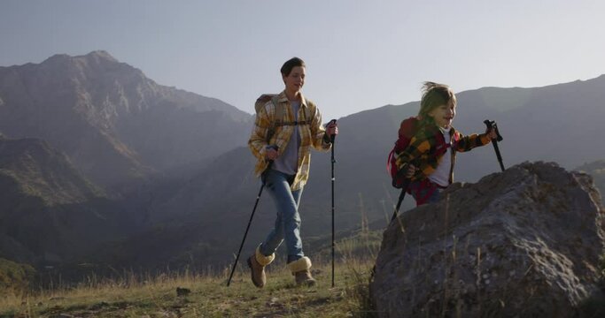 Mother and son conquer mountain, trekking poles backpacks. Healthy lifestyle mommy and kid hiking. Active and balanced way of living. Importance of supporting child in his aspirations. Care, love