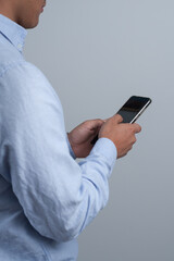 Technology. Young man using a cell phone on gray background
