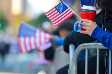 Spectators seen with American flags on the side of the street during the Annual Veterans Day Parade...