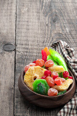 Candied fruits in wooden bowl on rustic background